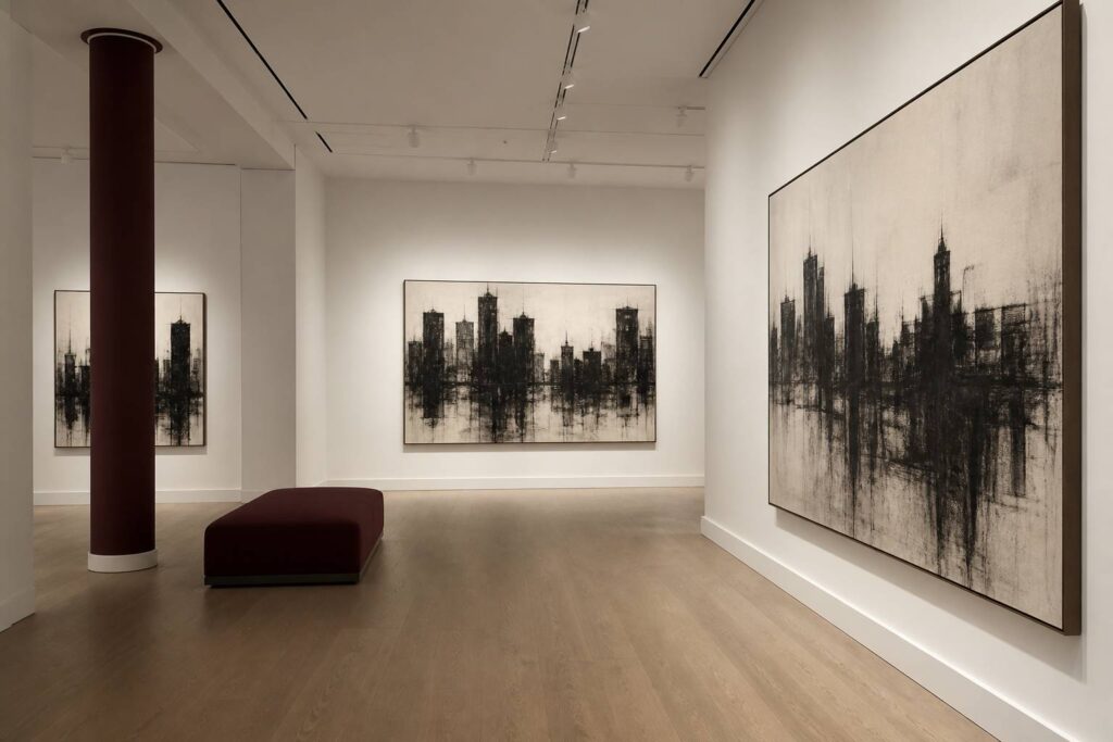 Salle de musée à cimaise blanche avec dessins au fusain de silhouettes urbaines