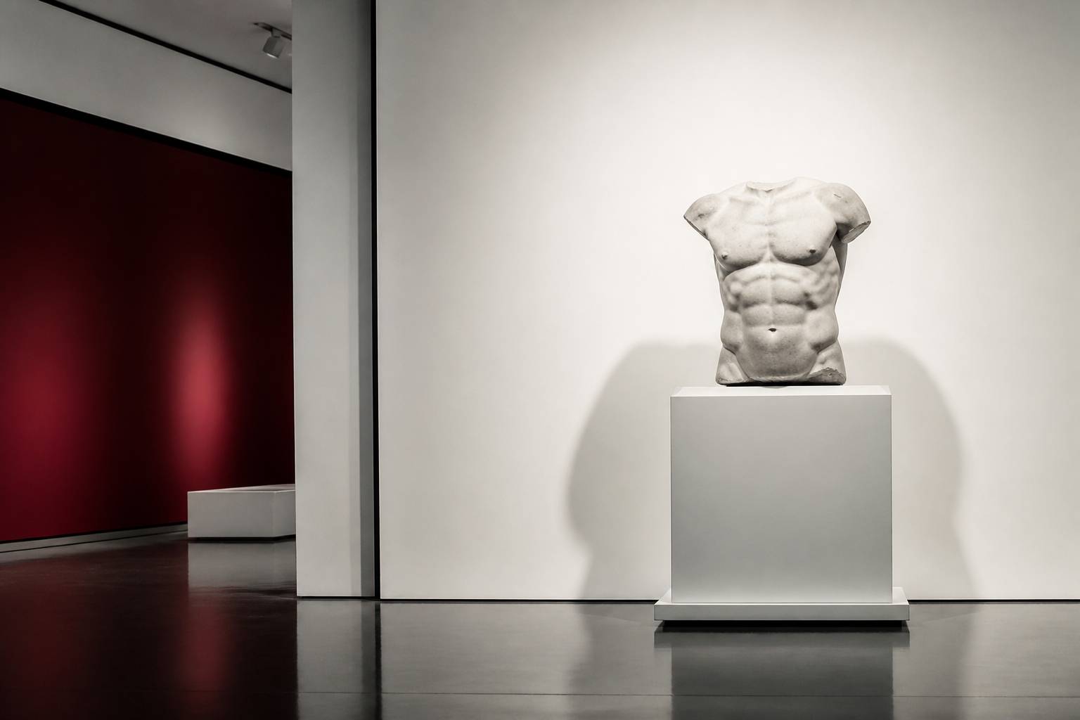 Torse grec antique en marbre exposé sur une cimaise blanche